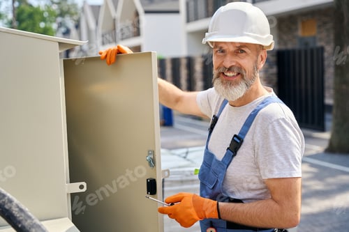 Preview: Male engineer posing for camera during electric switchboard installation