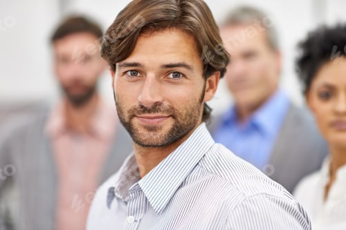 Preview: Cropped shot of a handsome young man standing with his colleagues blurred in the background