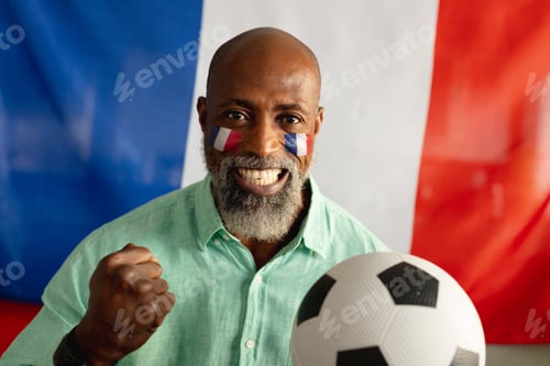 Preview: Portrait of happy senior african american man sitting with flag of france and football
