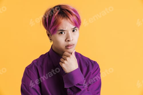 Preview: Asian boy with pink hair frowning and looking at camera