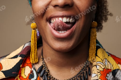Preview: Young black woman wearing earrings showing her tongue at camera