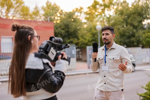 Preview: Reporter giving interview to camerawoman for news broadcast