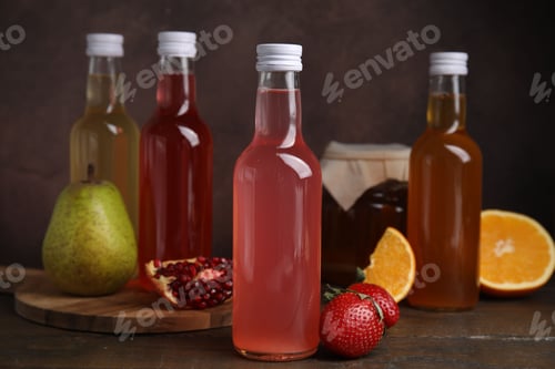 Preview: Delicious kombucha in glass bottles, jar and fresh fruits on wooden table