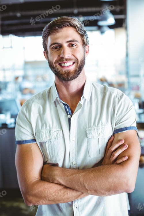 Preview: Young man with arms crossed looking the camera at the cafe
