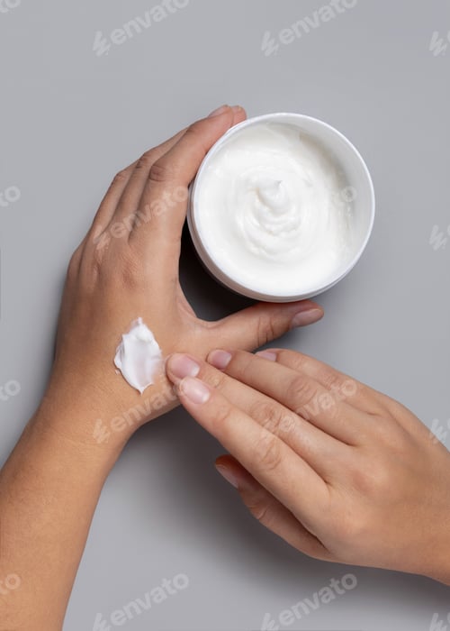 Preview: Woman applying protective cream on hand and holding a cosmetic jar in other hand, topview