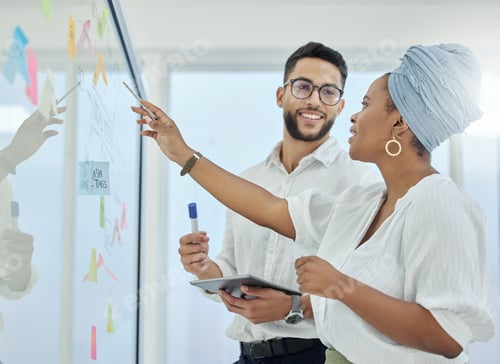 Preview: Cropped shot of two diverse young businesspeople working on a glass wipe board in the boardroom