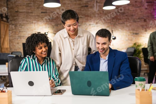 Preview: Multi ethnic team collaborating on laptops in modern office