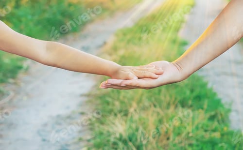 Child and Adult Hand in Nature Scene