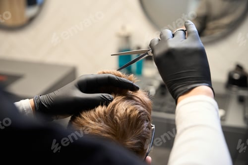 Preview: Cropped view of concentrated hairstylist working in hairdressing salon