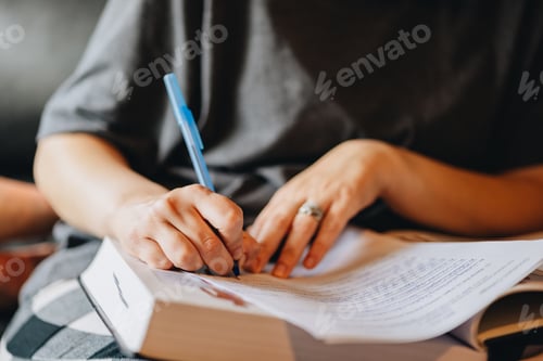 Preview: Millennial woman writing in notebook, studying for school while at home
