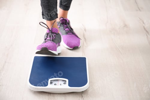 Preview: Woman measuring her weight using scales on floor