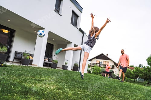 Preview: Young girl jumping high up in the air, missing to catch a ball - Family playing games outside the