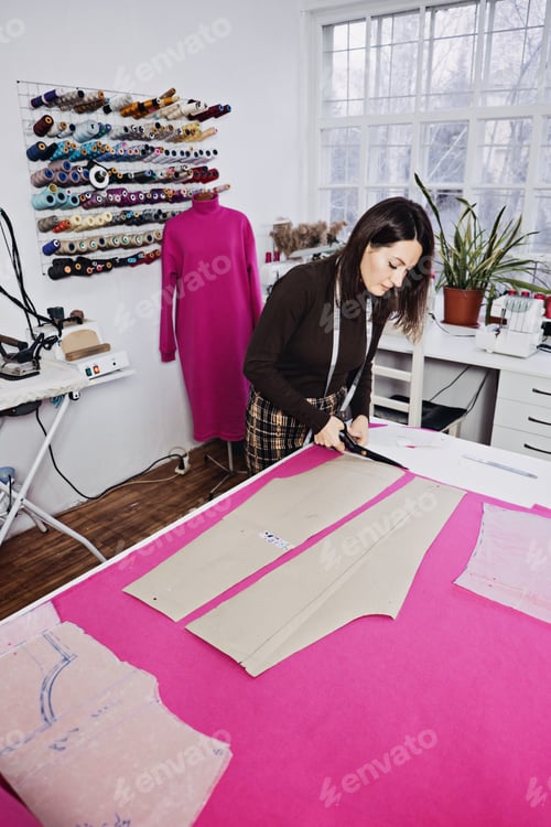 Preview: Seamstress working with sewing pattern on table in tailor shop