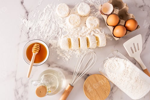 Preview: top view of freshly cooked cheesecakes and ingredients for cooking. eggs, honey, butter in a bottle.