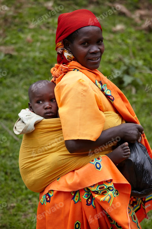 Preview: Mother carrying her child on her back in a vibrant rural setting.