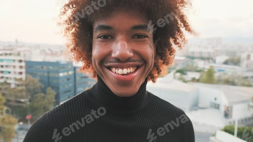 Preview: Close-up of young smiling guy posing at the camera while standing on the balcony