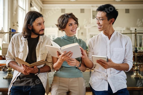 Preview: Group of young attractive multinational students happily studying together in library of university