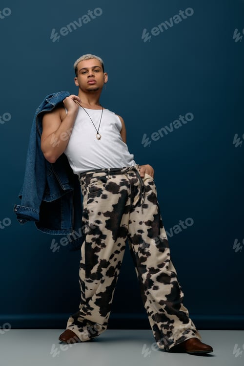 Preview: Young Black man sports a unique denim look against a blue background