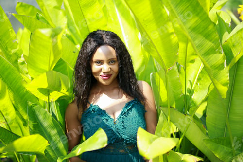 Preview: Cheerful young Afro American woman standing in tropical garden.