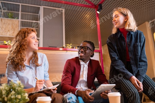 Preview: Three young cheerful managers discussing working questions at meeting