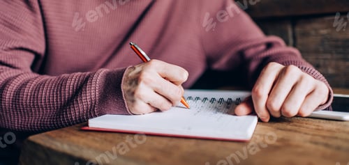 Preview: Unrecognizable man making notes of information studying in campus