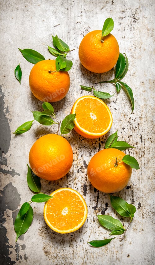 Preview: Fresh oranges with leaves. On rustic background.