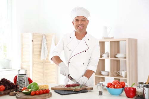 Preview: Professional chef cutting meat on table in kitchen