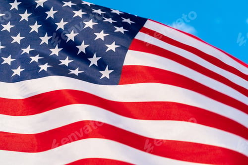 Preview: American flag waving in the wind against blue sky
