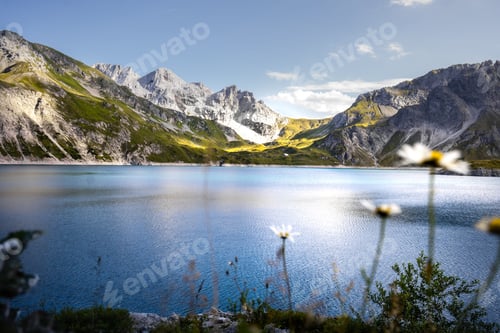 Preview: Tranquil Lunersee lake surrounded by lush green grass and jagged mountains in Austria
