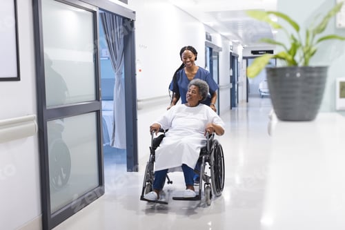 Preview: African american female doctor walking with senior female patient in wheelchair in hospital corridor
