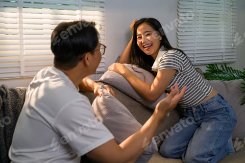 Preview: Asian couple chatting happily on sofa in living room