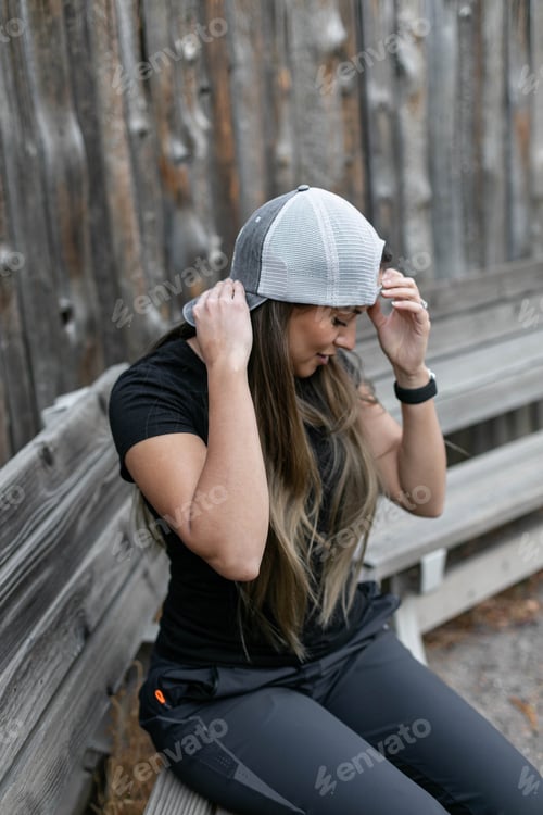 Preview: Young woman putting on a hat