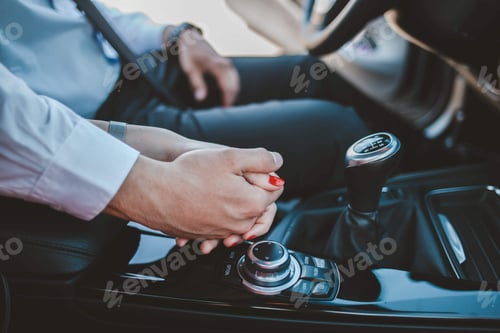 Preview: Closeup shot of a bride and groom holding hands in the car
