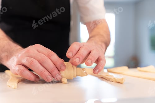 Preview: Hands of a man cooking croissants, shaping with the puff pastry, work at home