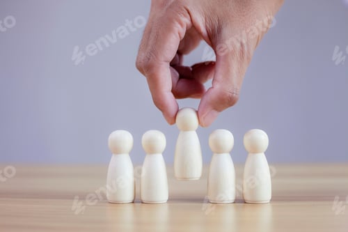 Preview: Businessman hands chooses best successful people wood model team.