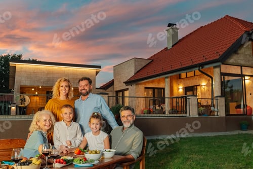 Preview: Family enjoying dinner in the backyard of their modern house during sunset