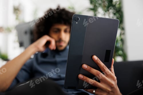 Preview: Young arab entrepreneur reading article on digital tablet