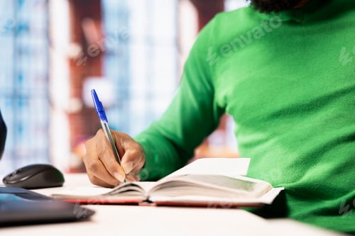 Preview: Close up of man writing personal notes in apartment workspace