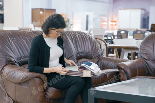 Preview: Adult woman buyer looking at a book with upholstery fabrics