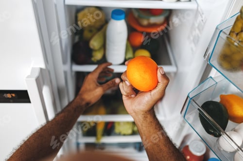 Preview: Male hands taking orange from fridge close up