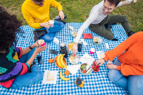 Preview: Four multiethnic friends having picnic park - Group of friends celebrating eating in a park bonding