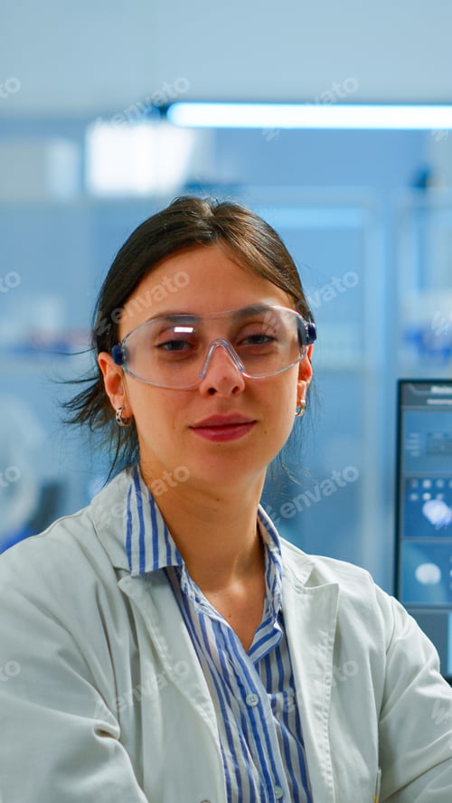 Preview: Chemist with lab coat sitting in laboratory looking at camera smiling