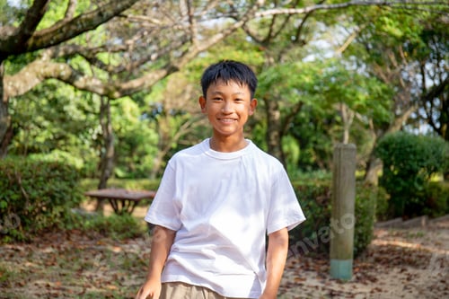 Preview: A 13 year old boy in a white teeshirt, smiling, outdoors in a park.