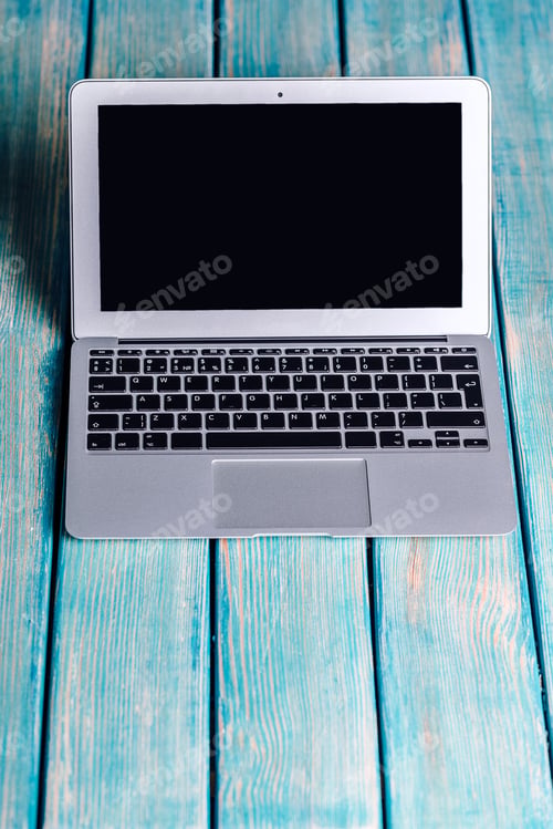 Preview: Laptop on blue wooden desk with black screen and minimalistic design highlighting a workspace