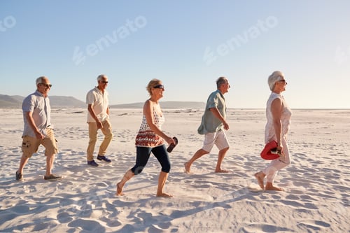 Preview: Side View Of Senior Friends Walking Along Sandy Beach On Summer Group Vacation
