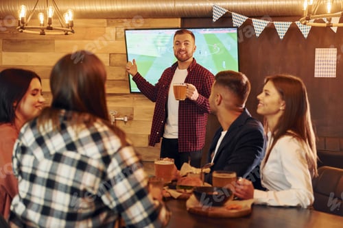Preview: Positive facial expression. Group of young friends sitting together in bar with beer
