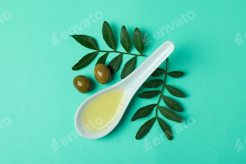 Preview: Spoon with oil, olives and twigs on mint background