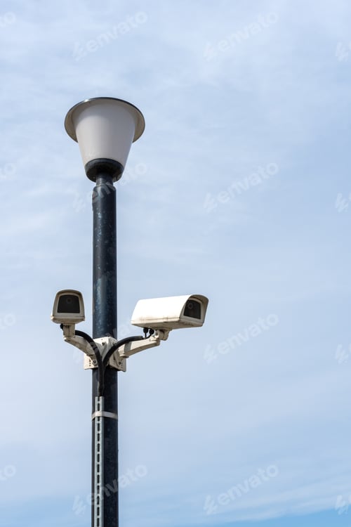 Preview: Surveillance cameras mounted on a lamp post against a blue sky. security cctv camera.