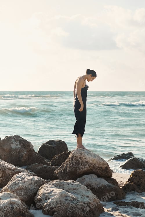 Preview: Woman in black sundress on miami beach rocks