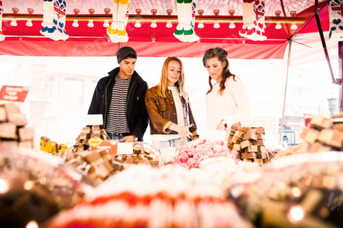 Preview: Friends browsing treats at a vibrant market stall.